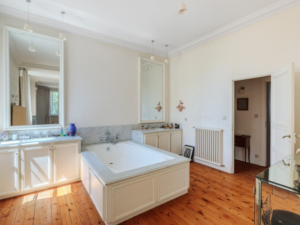 Salle de bain spacieuse avec baignoire, miroir et lumière naturelle