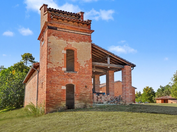Bâtiment en briques rouges avec toit en tuiles, entouré de verdure à Prunet.