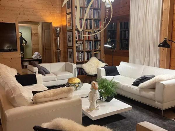 Intérieur d'un chalet à Megève avec salon moderne, canapés blancs, chandelier et bibliothèque.
