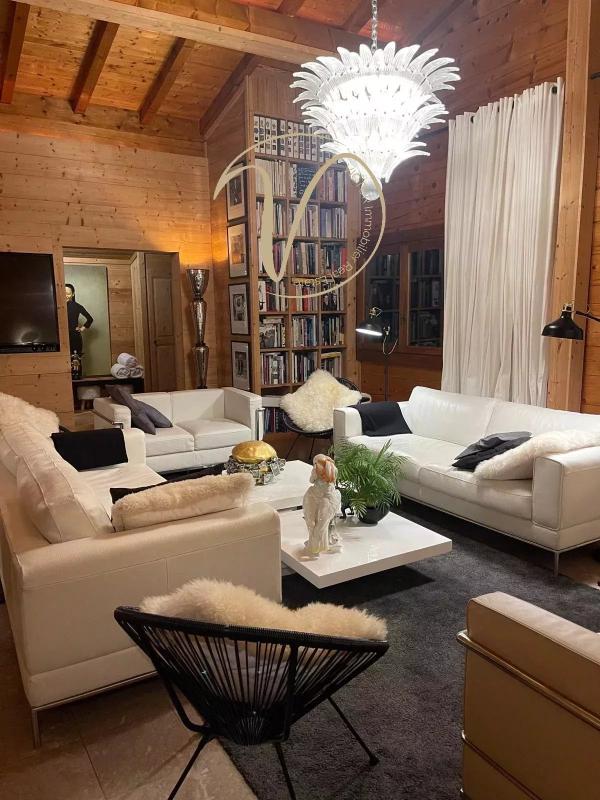 Intérieur d’un chalet à Megève Intérieur d'un chalet à Megève avec salon moderne, canapés blancs, chandelier et bibliothèque.