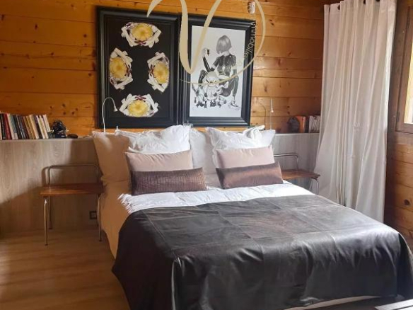 Chambre d'un chalet en bois avec lit double et décoration moderne.