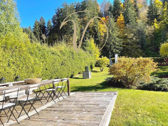 Jardin d'un chalet à Megève avec des chaises et des arbres en arrière-plan.