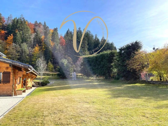 Chalet en bois avec un grand terrain herbeux, entouré d'arbres à Megève.