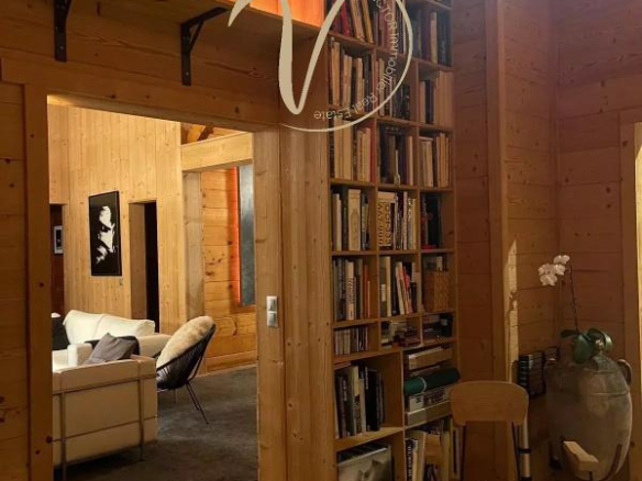 Intérieur d'un chalet en bois avec une bibliothèque et un coin salon.