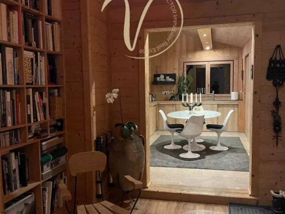 Intérieur d'un chalet en bois avec une salle à manger moderne et une bibliothèque.