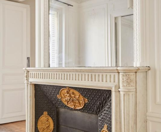 Cheminée en marbre avec décorations dorées dans un appartement à Paris.