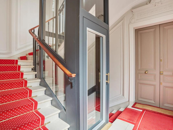 Cage d'escalier avec ascenseur vitré dans un immeuble bourgeois à Paris 8ème.