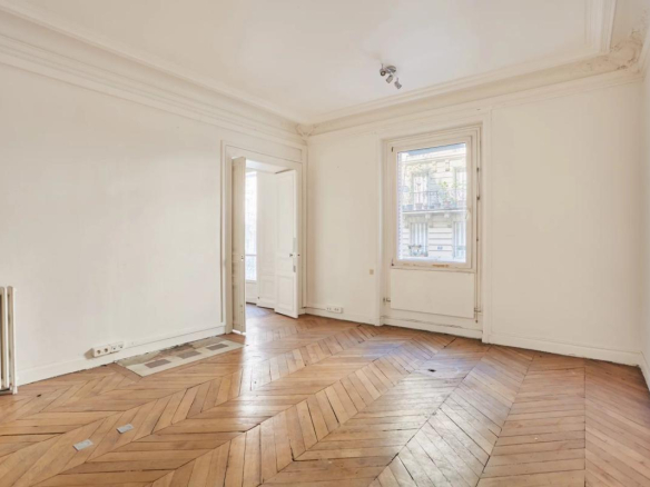 Intérieur d'un appartement à rénover avec parquet en points de Hongrie et murs blancs, Paris 8ème.