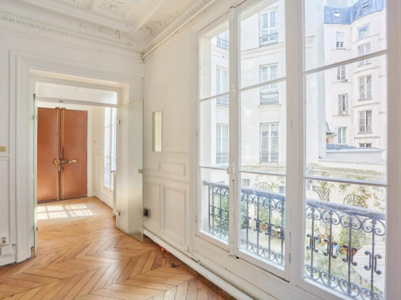 Intérieur d'un appartement à Paris avec fenêtres et parquet en bois.