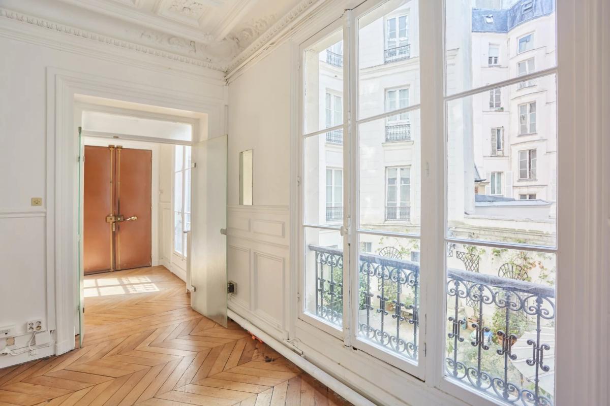 Bel appartement à rénover à Paris 8ème Intérieur d'un appartement à Paris avec fenêtres et parquet en bois.