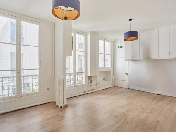 Intérieur d'un appartement à rénover de 200 m² à Paris, avec parquet et fenêtres donnant sur la rue.