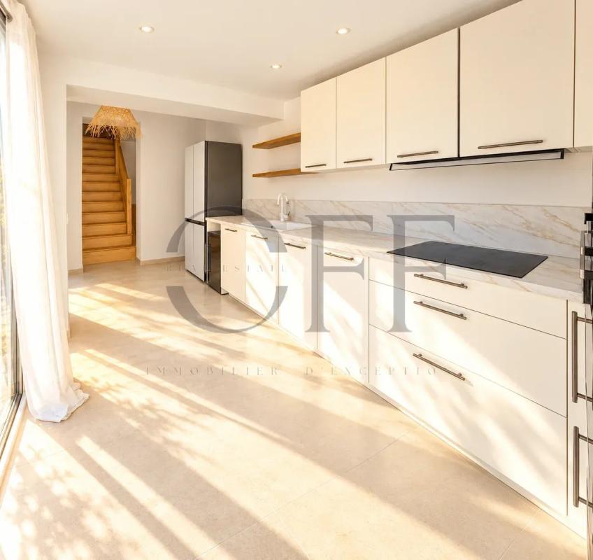 Cuisine moderne dans une maison à Le Rove Intérieur d'une cuisine moderne avec des meubles clairs et un accès à un escalier en bois.