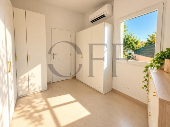 Intérieur d'une maison avec des placards blancs et une fenêtre laissant entrer la lumière.