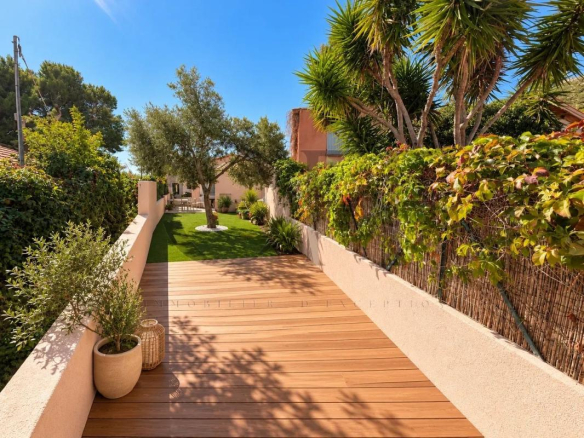 Allée en bois menant à un jardin verdoyant avec des plantes et des arbres.