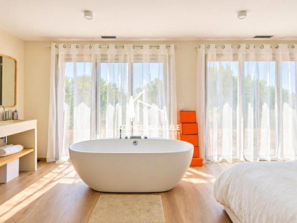 Chambre lumineuse avec baignoire et grandes fenêtres dans une villa contemporaine à Nîmes.
