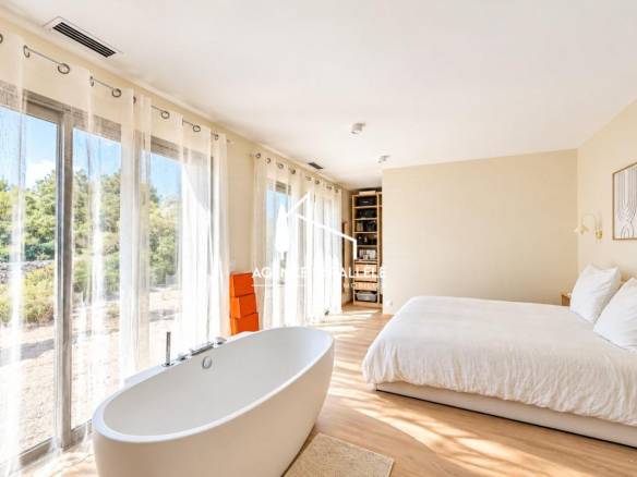 Chambre moderne avec baignoire et grandes fenêtres donnant sur un jardin à Nîmes.