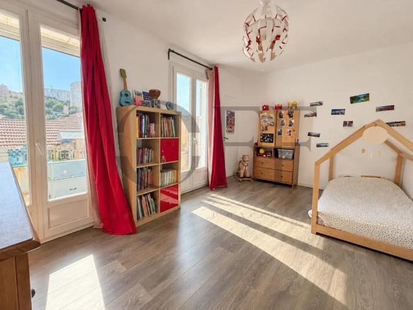 Chambre lumineuse dans une maison de ville à Marseille, avec des livres et un lit enfant.