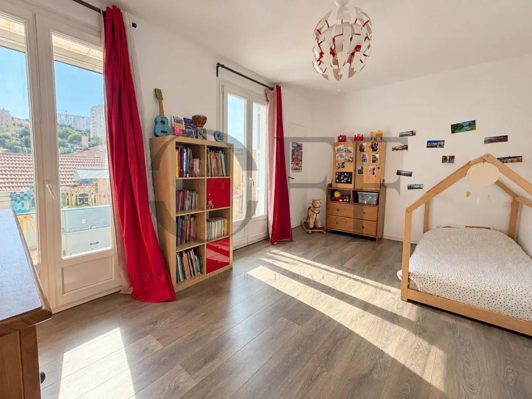 Chambre d’une maison de ville à Marseille Chambre lumineuse dans une maison de ville à Marseille, avec des livres et un lit enfant.