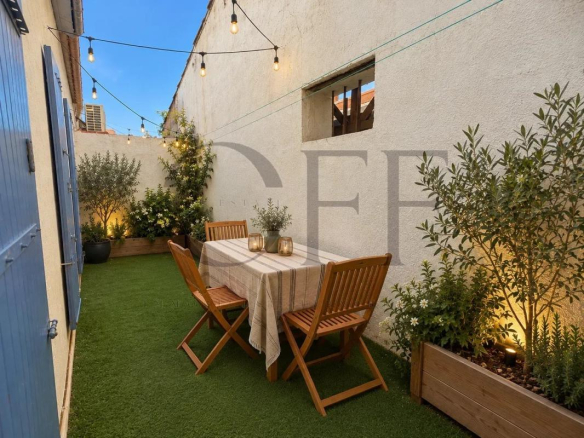 Terrasse d'une maison de ville à Marseille avec table et chaises en bois, éclairage extérieur