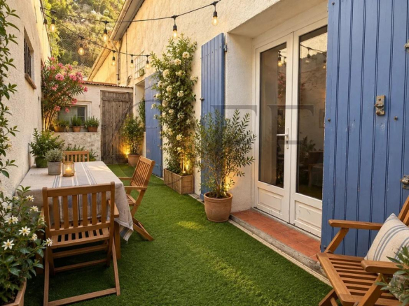 Cour intérieure d'une maison de ville à Marseille avec mobilier en bois et plantes.