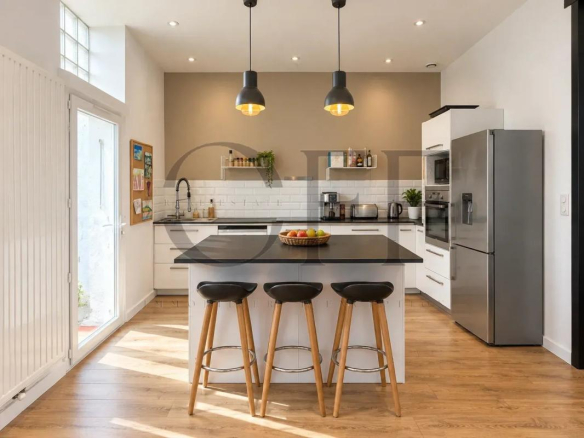Cuisine moderne avec îlot central et bar, éclairage suspendu, dans une maison de ville rénovée.