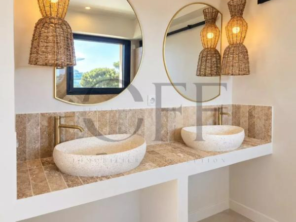 Salle de bain moderne avec deux lavabos et miroirs ronds, éclairage en osier.