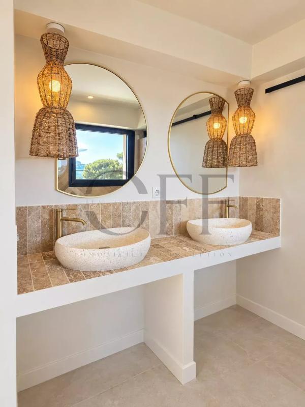 Salle de bain moderne avec deux lavabos et miroirs ronds, éclairage en osier.