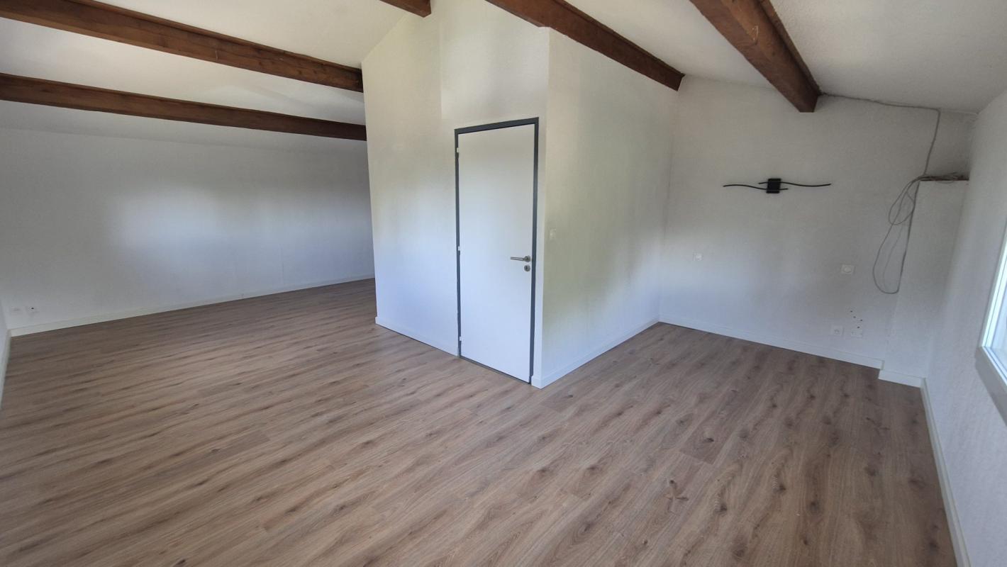 Intérieur d'une maison spacieuse avec un sol en bois et des poutres apparentes.