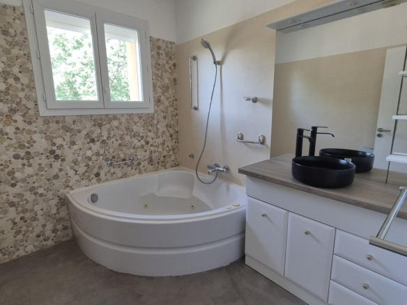 Salle de bain moderne avec baignoire et double vasque dans une maison à Saint-Aunès.