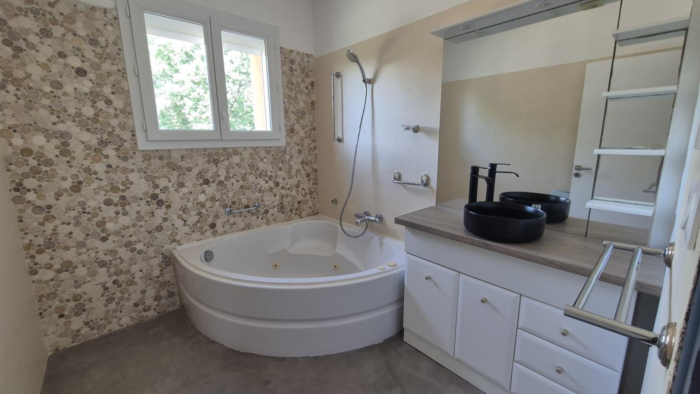 Salle de bain moderne avec baignoire et double vasque dans une maison à Saint-Aunès.