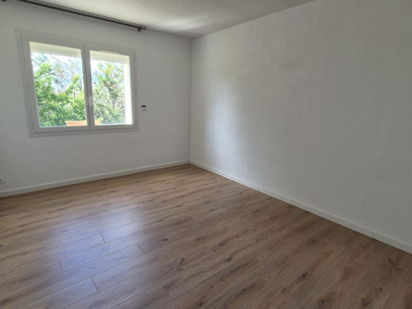 Intérieur d'une maison à Saint-Aunès avec un sol en bois et des murs blancs.