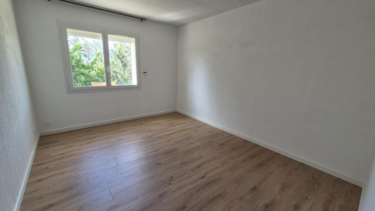 Intérieur d'une maison à Saint-Aunès avec un sol en bois et des murs blancs.