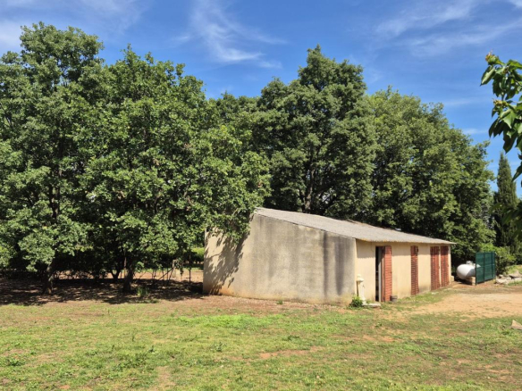 Bâtiment en extérieur sur un terrain arboré à Saint-Aunès, avec des arbres autour.