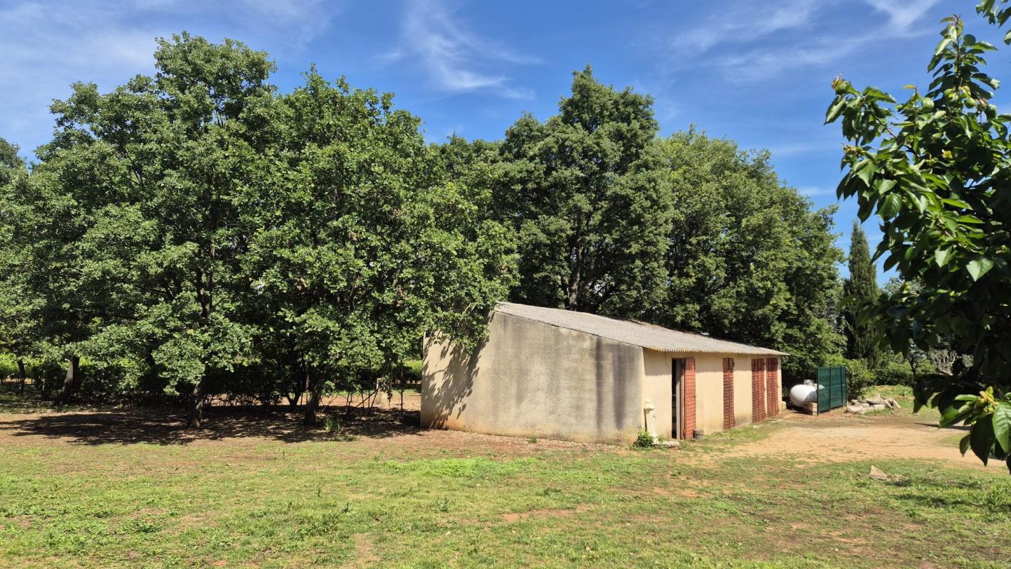 Bâtiment en extérieur sur un terrain arboré à Saint-Aunès, avec des arbres autour.