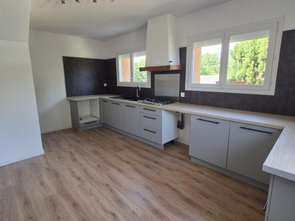 Cuisine moderne et spacieuse d'une maison à Saint-Aunès, avec des meubles gris et un plan de travail en bois.