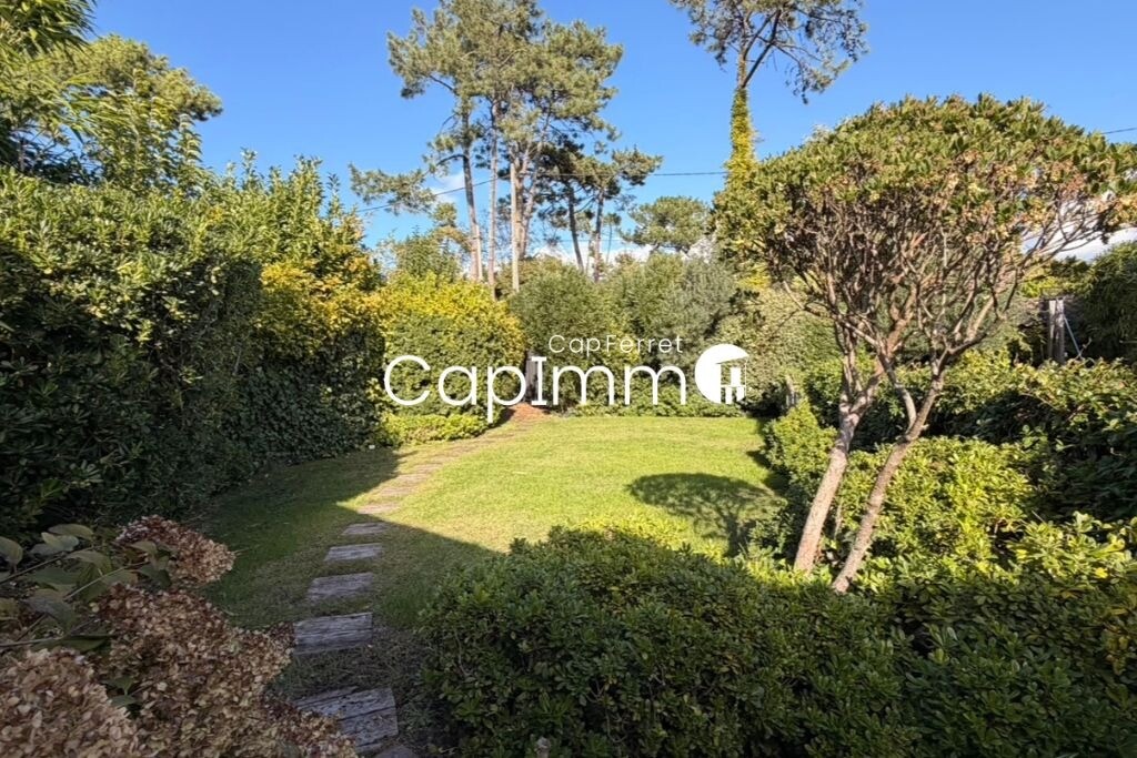 Garden of the villa in Lège-Cap-Ferret Lush garden of a villa in Lège-Cap-Ferret with stone path and trees.