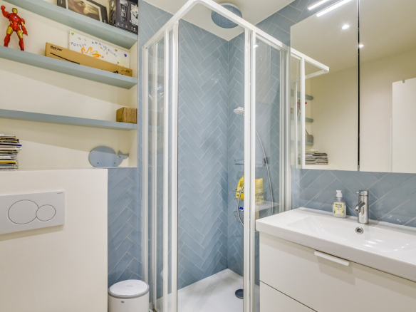Salle de bain moderne avec douche et lavabo dans un appartement rénové à Paris 15ème.