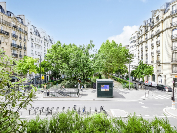 Vue dégagée sur le Square Adolphe Chérioux à Paris, avec des arbres et des bâtiments en arrière-plan.