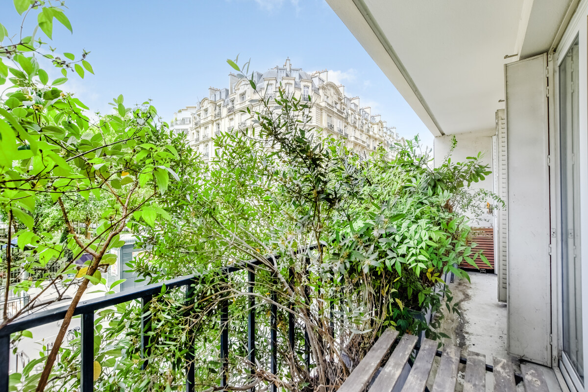 Balcon d’un appartement rénové à Paris 15ème Balcon verdoyant d'un appartement à Paris 15ème avec vue dégagée sur un immeuble.