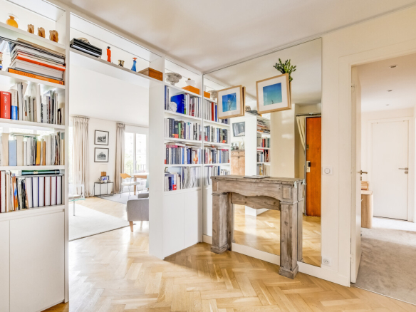Intérieur d'un appartement rénové avec bibliothèque et miroir, lumineux et spacieux.