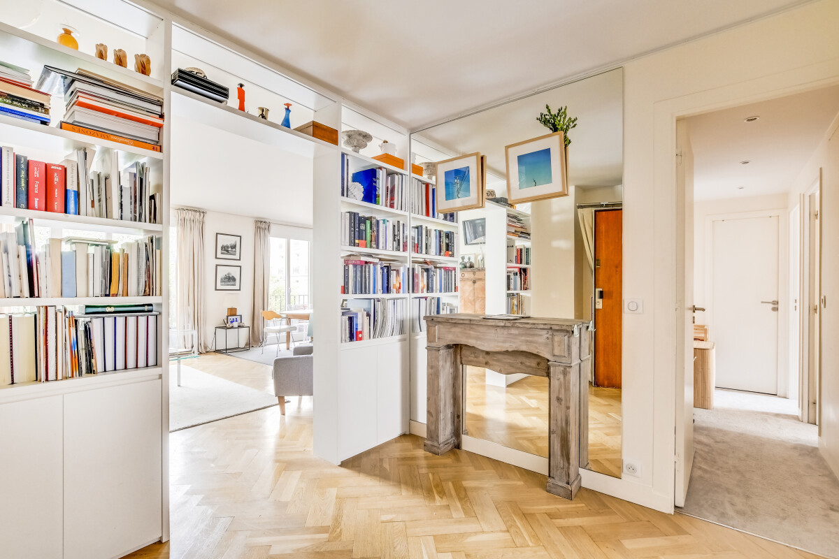 Appartement rénové à Paris 15ème Intérieur d'un appartement rénové avec bibliothèque et miroir, lumineux et spacieux.