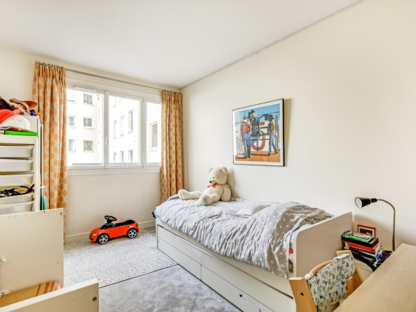 Chambre d'un appartement rénové à Paris 15ème, lumineuse avec un lit et un ours en peluche.