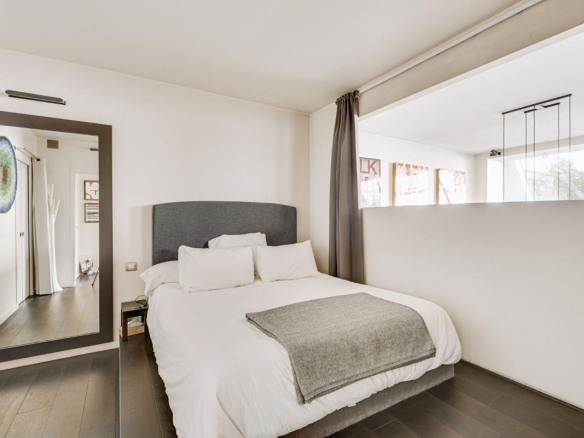 Chambre d'un duplex à Paris, lit double avec décoration moderne et lumière naturelle.
