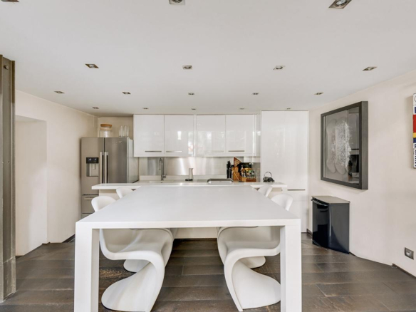 Cuisine moderne avec table à manger et électroménagers dans un duplex à Paris 16ème.