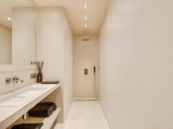 Salle d'eau moderne avec douche et lavabo dans un duplex à Paris.