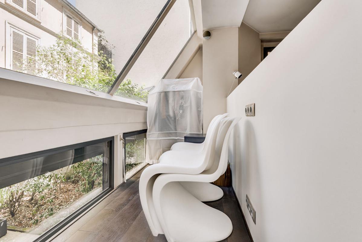 Intérieur d’un duplex à Paris Intérieur d'un duplex à Paris avec des chaises blanches et une vue sur un espace extérieur.