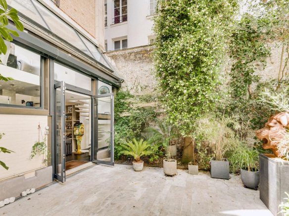 Terrasse d'un duplex à Paris avec plantes et sculptures, accès depuis le salon lumineux.