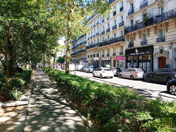 Tree-lined street with cars and shops in the 9th arrondissement of Paris.