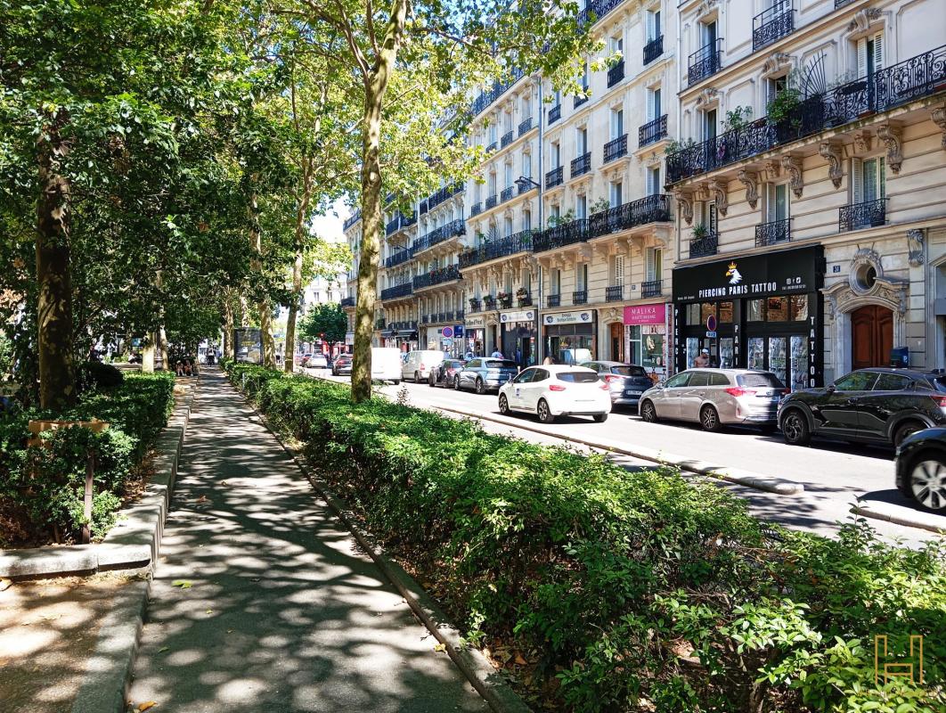 View of a street in the 9th arrondissement of Paris Tree-lined street with cars and shops in the 9th arrondissement of Paris.