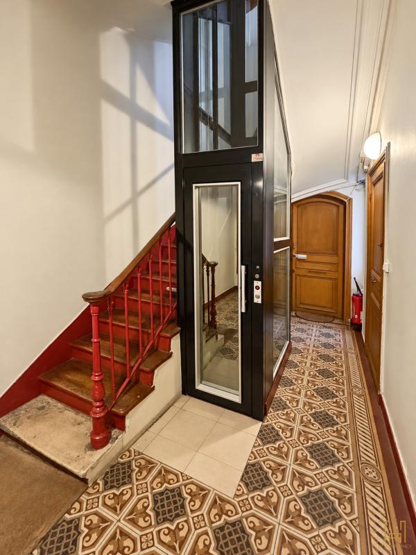 Elevator in a Haussmannian building Glass elevator in a Haussmannian building lobby with staircase and decorative tiling.